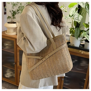 Detailed close-up of straw tote bag showing woven texture and brown leather strap detail