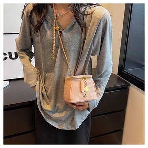 Detail of pink croc-pattern mini bag with gold chain strap worn by a model