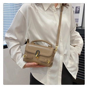 Close-up of khaki leather handbag featuring gold oval clasp and elegant stitching detail