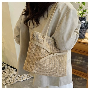 Detail of a large straw tote bag with V-weave texture and beige leather accents on model