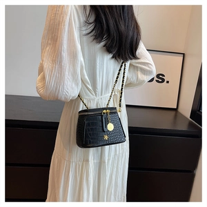 Detail of black crocodile texture mini bag with gold flower charm and chain strap