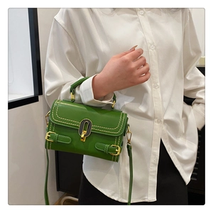 Detail view of the green embossed leather handbag with golden U-shaped lock and stitching