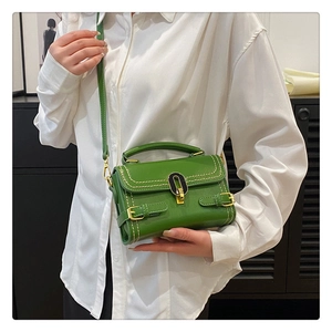 Close-up of bright green embossed handbag with black and gold twist lock and stitching