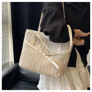 Close-up of a large woven straw tote bag with V-shaped patterns and leather strap details