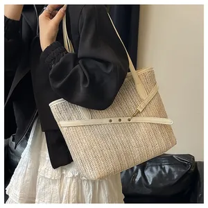Close-up of woven texture on large straw tote bag with white faux leather straps and gold hardware