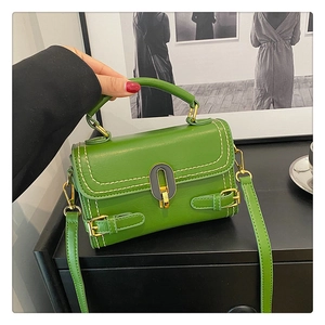 Close-up of grass green embossed leather handbag with golden metal buckle detail
