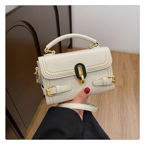 Detailed view of cream leather handbag featuring contrast yellow stitching and gold hardware