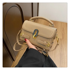 Detail of khaki stone-embossed handbag with gold-tone oval twist lock and strap