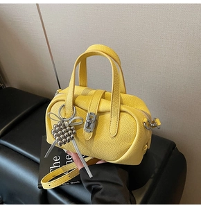 Yellow pebble leather crossbody bag with silver hardware and decorative charm handle