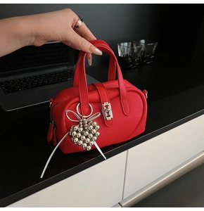 Detail of red lychee grain handbag with silver heart beads and elegant silk ribbon