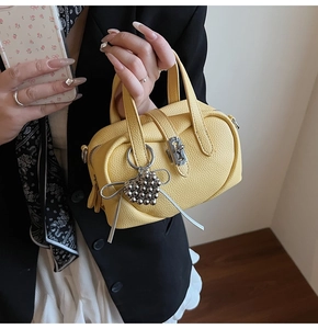 Detail of yellow pebbled leather handbag with silver heart charm and bow ribbon