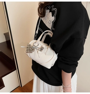 Detail of white lychee leather bag featuring a beaded heart charm and metal lock
