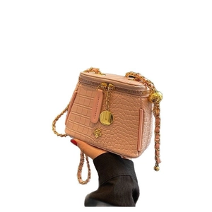 Pink croc-embossed mini bucket bag with gold chain strap and floral metal detail