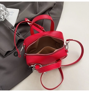 Detail view of red lychee grain leather bag interior with silver zipper and metal ball charm