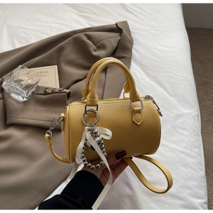 Détail du sac polochon en cuir litchi jaune avec ferrures argentées et nœud en soie