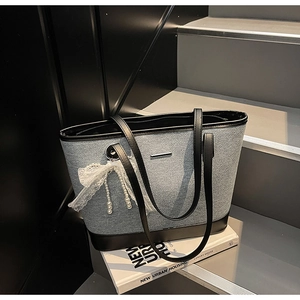Détail du sac cabas bicolore avec pendentif nœud en dentelle et perles décoratives