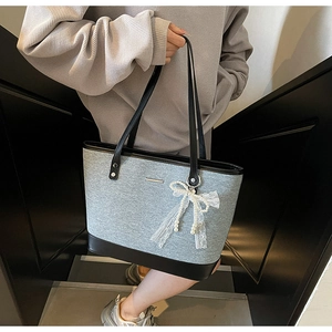 Détail du sac cabas en tissu gris et cuir noir avec breloque nœud en perles