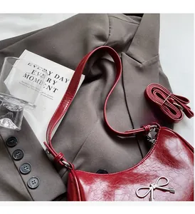 Detailed close-up of dark red bow shoulder bag texture and silver metal hardware