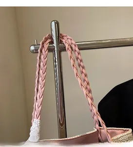 Detail of pink braided shoulder strap and white lace trim on a straw tote bag
