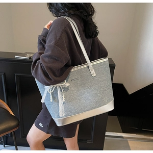 Détail du sac cabas en denim bleu avec garniture argentée et nœud en dentelle