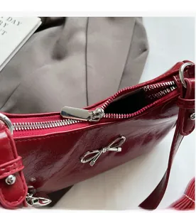 Close-up of smooth silver zipper and glossy red wrinkled leather handbag detail