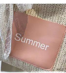 Detail of straw woven tote featuring a pink Summer patch and white lace ribbon trim