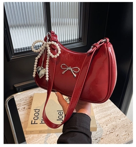 Detail of red patent leather shoulder bag with silver bow and pearl heart charms