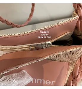 Close-up of a smooth metal zipper and pink leather trim on a woven straw tote bag