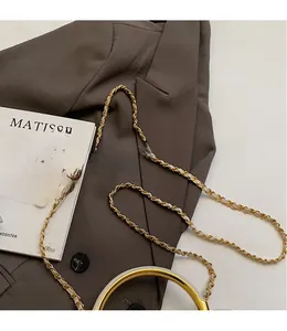Detail of golden metal chain strap with woven white leather and vintage buckle