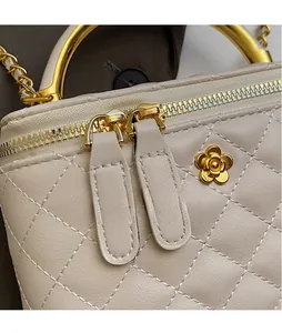 Detail of cream quilted leather bucket bag with gold flower clasp and dual smooth zippers