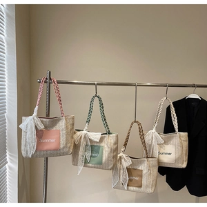 Detail of four colorful straw tote bags with Summer logo and lace bow accents