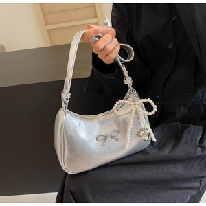 Detail of silver metallic hobo bag featuring a metal bow and pearl heart pendant