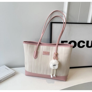 Detail of pink and beige tote bag with wave texture and cute white plush charm