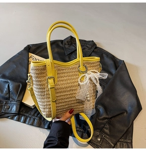 Close-up of woven straw tote with yellow leather trim and pearl bow charm accessory