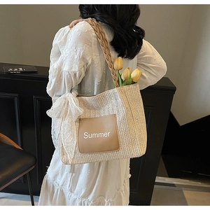 Detail of beige straw tote bag with brown leather Summer patch and white lace bow