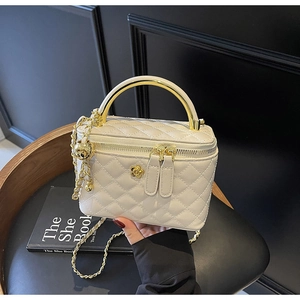 Detail of white quilted bucket bag with golden flower charm and metal arch handle