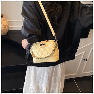 Close-up of quilted pale yellow leather shoulder bag featuring silver chain and turn-lock