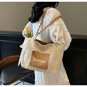 Close-up of woven straw tote bag featuring Summer leather patch and lace bow details