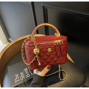 Macro detail of dark red quilted bucket bag with golden metal handle and chain strap