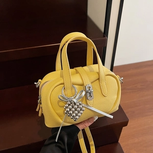 Bright yellow Boston pillow handbag with silver heart charm and crossbody strap