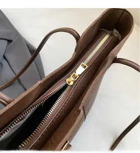 Close-up of smooth gold metal zipper and textured brown leather on vintage tote bag