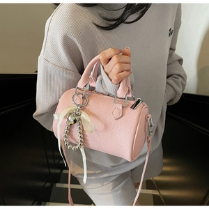 Détail du sac Boston en cuir rose avec pendentif coeur argenté et nœud décoratif