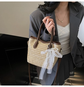 Detail of straw tote bag with brown leather handles and white lace bow and pearls