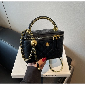 Detail of black quilted bucket bag with gold handle and chain link shoulder strap