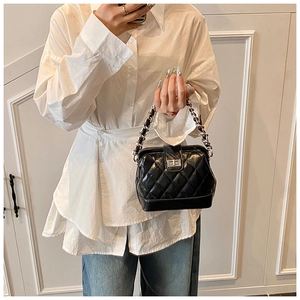Detail of black quilted leather handbag with metal chain handle and metal twist lock