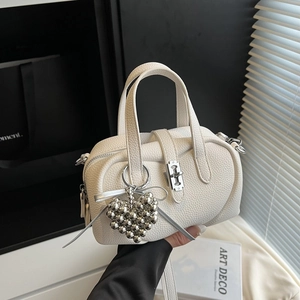White lychee leather handbag with dual handles and silver heart pendant in a chic setting