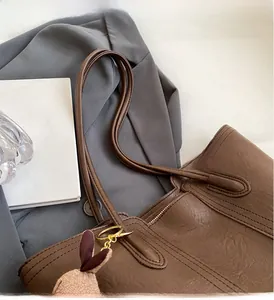 Detail of a brown tote bag featuring durable handles and a cute plush rabbit charm