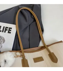Detail of chevron texture beige tote bag with long brown straps and fuzzy ball charm