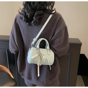 Détail du sac cylindre bleu clair avec perles argentées et nœud en soie blanc
