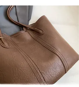 Detail of the brown tote bag featuring soft wrinkled faux leather and reinforced stitching